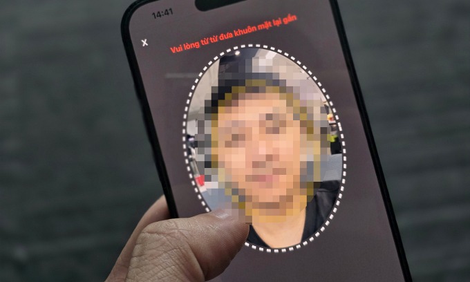 alt=A person holding up a phone with a face on it, posing a potential risk due to a new virus targeting iOS users in Vietnam and Thailand.