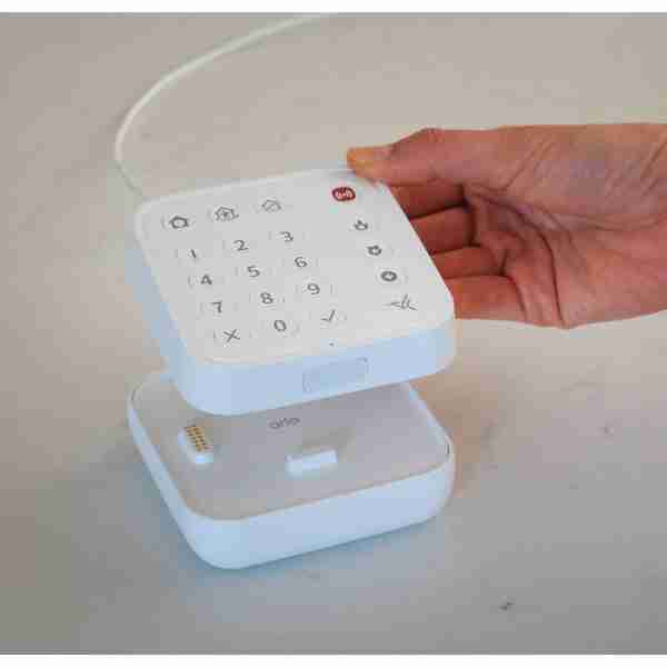 alt=1. A person holds a small white box and remote control, showcasing the Arlo Cellular & Battery Backup for home security.