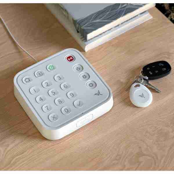 alt=1. A white keypad and Arlo remote control placed on a table, showcasing a modern and sleek design.