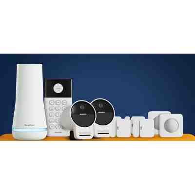 alt=A collection of SimpliSafe home security devices, including cameras, a keypad, and sensors, displayed on an orange surface against a blue background.