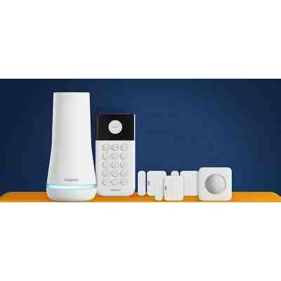 alt=A home security system from SimpliSafe, featuring a base station, keypad, and multiple sensors on a vibrant orange surface against a dark background.