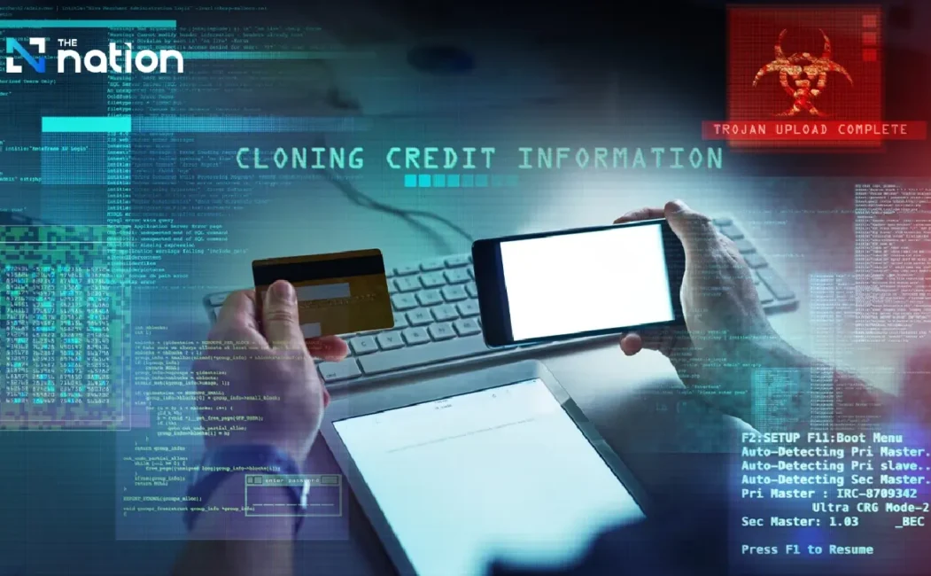 alt=Hands holding a credit card and smartphone with digital overlays showing "Cloning Credit Information" and a "Trojan Upload Complete" warning.