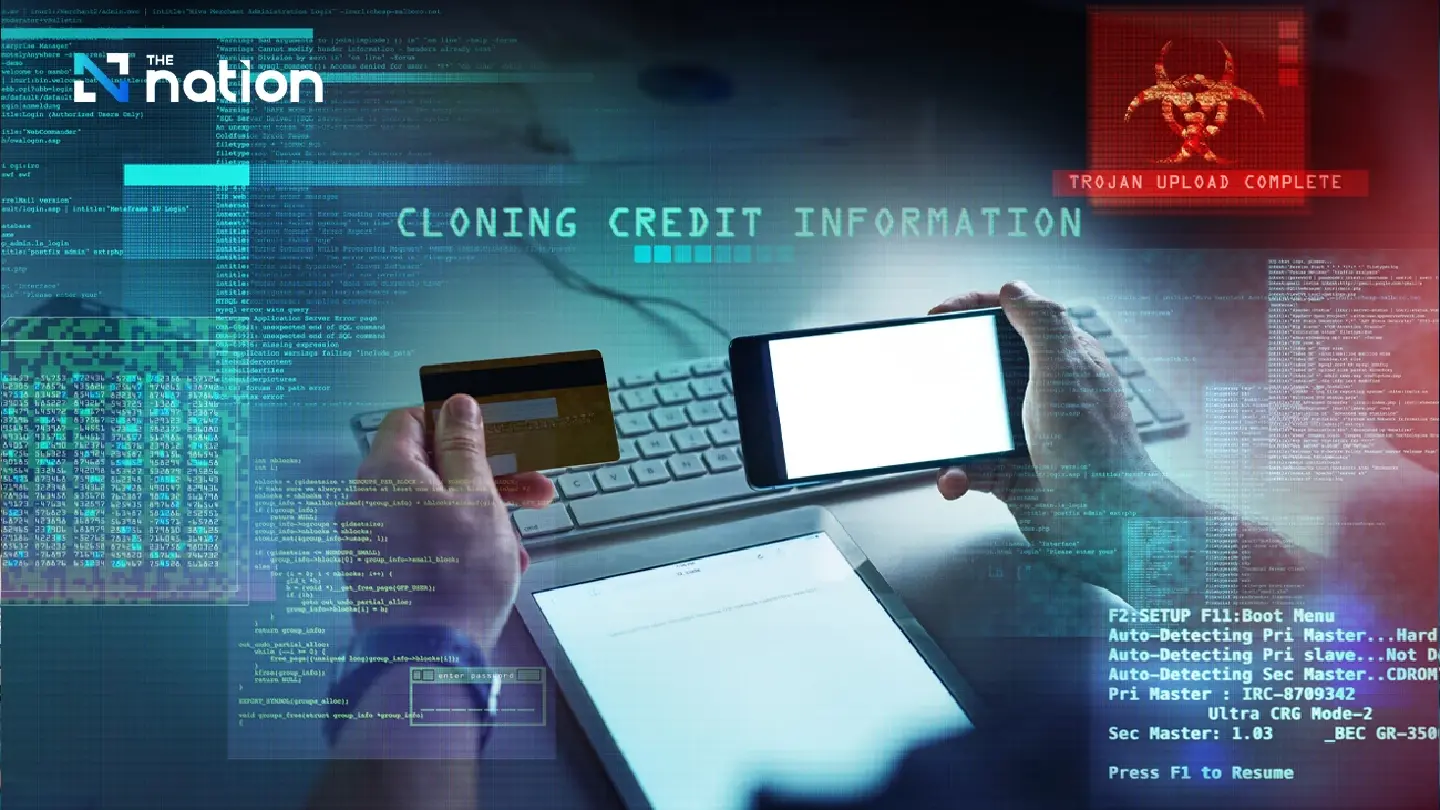 alt=Hands holding a credit card and smartphone with digital overlays showing "Cloning Credit Information" and a "Trojan Upload Complete" warning.