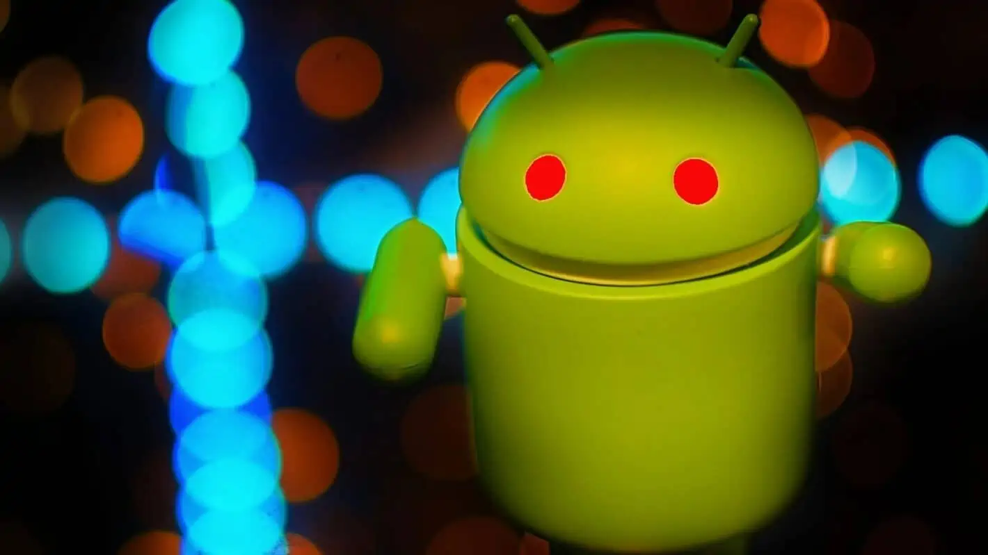 alt=Green Android figurine with glowing red eyes against a background of blurred blue and orange lights.